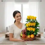 Mujer joven sonriente sosteniendo una canasta de mimbre con rosas amarillas y frutas variadas en una sala de estar luminosa