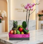 Arreglo ANTONELLO con orquídea Phalaenopsis rosa y frutas selectas como piña, manzanas, kiwis, mangos y aguacates, presentado