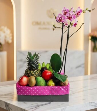 Arreglo ANTONELLO con orquídea Phalaenopsis rosa y frutas selectas como piña, manzanas, kiwis, mangos y aguacates, presentado
