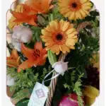 Primer plano extremo del Arreglo Basilio, mostrando la textura hiperrealista de rosas, lirios y gerberas con gotas de rocío s