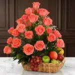 Elegante cesta de regalo ABRAMIO con rosas salmón vibrantes y una selección de frutas frescas como uvas, manzanas y peras, so