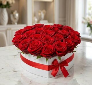 Arreglo floral CAMILA con 24 rosas rojas premium en una elegante caja blanca en forma de corazón, adornada con un lazo rojo,