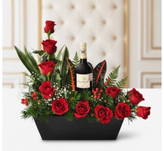 Arreglo floral CINZIA con 12 rosas rojas frescas, follaje verde variado y una botella de vino tinto, presentado en una base n