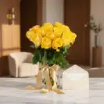 Arreglo floral Elisabetta con 18 rosas amarillas frescas en jarrón de cristal, cinta dorada, tarjeta de regalo en sobre crema