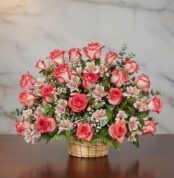 Arreglo floral Emilia con 32 rosas blush frescas, alstroemerias blancas y follaje verde en una canasta de mimbre sobre una me