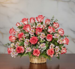 Arreglo floral Emilia con 32 rosas blush frescas, alstroemerias blancas y follaje verde en una canasta de mimbre sobre una me
