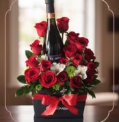 Arreglo floral ENNIO con rosas rojas vibrantes, alstroemerias blancas y vino tinto, presentado en caja negra con lazo rojo.