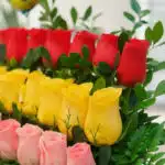 Primer plano extremo de un Arreglo Floral Escala con rosas rojas, amarillas y rosadas, mostrando texturas hiperrealistas y su