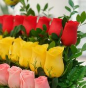 Primer plano extremo de un Arreglo Floral Escala con rosas rojas, amarillas y rosadas, mostrando texturas hiperrealistas y su