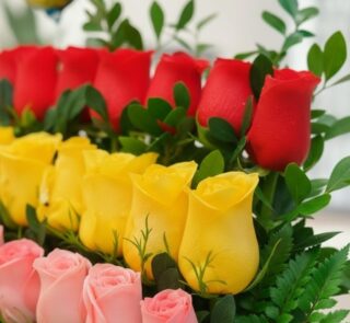 Primer plano extremo de un Arreglo Floral Escala con rosas rojas, amarillas y rosadas, mostrando texturas hiperrealistas y su