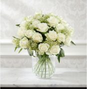 Arreglo floral Estefanía con 24 rosas blancas frescas en un jarrón de cristal sobre una mesa de mármol, con un fondo elegante