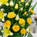 Primer plano extremo de un arreglo floral exótico Amaretto con rosas amarillas, lirios blancos y gerberas amarillas, mostrand