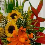 Primer plano extremo de Arreglo Floral Exótico Antídoto con girasoles, heliconias rojas, flores de jengibre y lazo naranja, c
