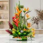 Arreglo floral exótico Apolo con heliconias, aves del paraíso y follaje verde, incluyendo una botella de Corona Extra, sobre