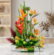 Arreglo floral exótico Apolo con heliconias, aves del paraíso y follaje verde, incluyendo una botella de Corona Extra, sobre