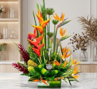 Arreglo floral exótico Apolo con heliconias, aves del paraíso y follaje verde, incluyendo una botella de Corona Extra, sobre