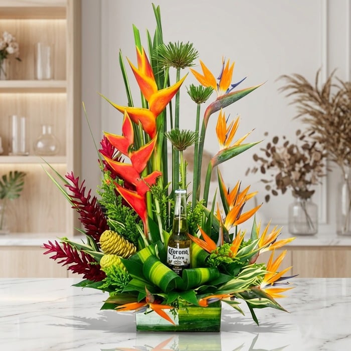 Arreglo floral exótico Apolo con heliconias, aves del paraíso y follaje verde, incluyendo una botella de Corona Extra, sobre