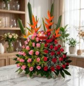 Impresionante arreglo floral exótico con rosas rojas y rosadas vibrantes, aves del paraíso y follaje exuberante, sobre una su
