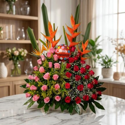 Impresionante arreglo floral exótico con rosas rojas y rosadas vibrantes, aves del paraíso y follaje exuberante, sobre una su