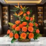 Impresionante arreglo floral exótico con vibrantes rosas naranjas y aves del paraíso, presentado en una cesta de mimbre sobre