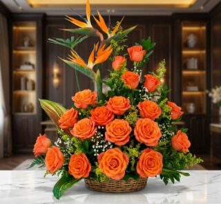 Impresionante arreglo floral exótico con vibrantes rosas naranjas y aves del paraíso, presentado en una cesta de mimbre sobre