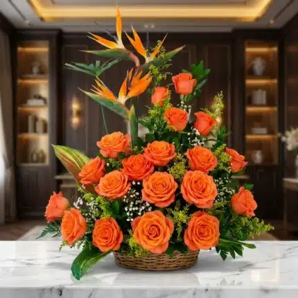 Impresionante arreglo floral exótico con vibrantes rosas naranjas y aves del paraíso, presentado en una cesta de mimbre sobre