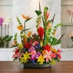 Arreglo floral exótico Fusión con aves del paraíso, lirios, orquídeas y flores tropicales vibrantes sobre mármol pulido, esti