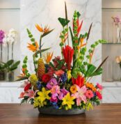 Arreglo floral exótico Fusión con aves del paraíso, lirios, orquídeas y flores tropicales vibrantes sobre mármol pulido, esti