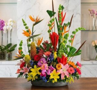 Arreglo floral exótico Fusión con aves del paraíso, lirios, orquídeas y flores tropicales vibrantes sobre mármol pulido, esti