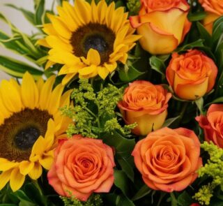 Primer plano extremo de un arreglo floral exótico con girasoles amarillos y rosas naranjas, mostrando texturas hiperrealistas