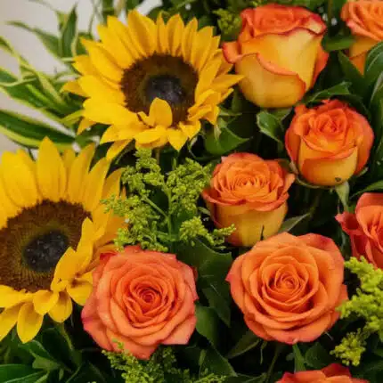 Primer plano extremo de un arreglo floral exótico con girasoles amarillos y rosas naranjas, mostrando texturas hiperrealistas