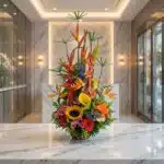 Arreglo floral exótico Mi Flechazo con aves del paraíso, girasoles, calas y follaje vibrante sobre una superficie de mármol e