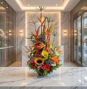 Arreglo floral exótico Mi Flechazo con aves del paraíso, girasoles, calas y follaje vibrante sobre una superficie de mármol e