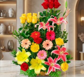 Arreglo floral exótico Paraíso con lirios rosados, rosas rojas y amarillas, y gerberas de varios colores, sobre una superfici