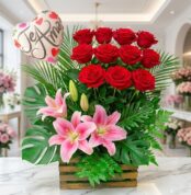 Arreglo floral exótico primaveral con rosas rojas vibrantes, lirios rosados abiertos y follaje exuberante, sobre mármol en fl