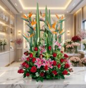 Arreglo floral exótico Siempre Juntos con lirios rosados, rosas rojas vibrantes y aves del paraíso, sobre una superficie de m