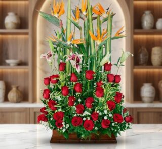 Impresionante arreglo floral exótico Tucana con rosas rojas vibrantes, lirios blancos y rosados, y aves del paraíso, sobre un