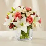 Arreglo floral Fabrizia con rosas rosadas, lirios blancos, claveles crema y bayas rojas en un jarrón de cristal cuadrado, ide