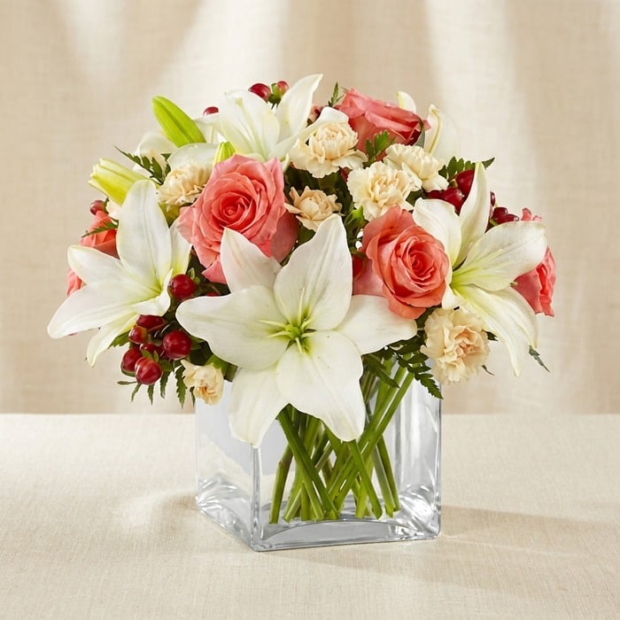 Arreglo Floral Fabrizia: Rosas Rosadas y Lirios Blancos para Regalar Arreglo floral Fabrizia con rosas rosadas, lirios blancos, claveles crema y bayas rojas en un jarrón de cristal cuadrado, ide