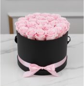 Arreglo floral Francesca con 21 rosas rosadas preservadas en una caja cilíndrica negra con lazo rosa, ideal para regalo.