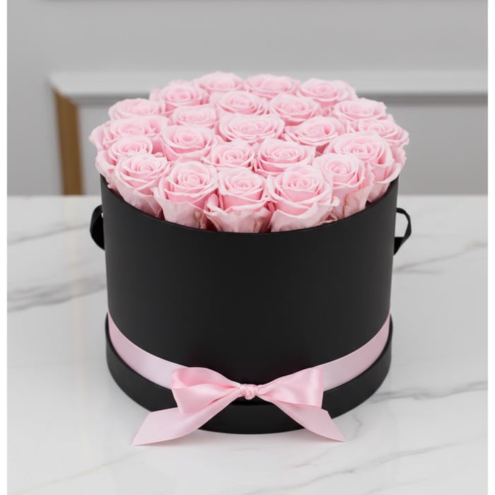 Arreglo floral Francesca con 21 rosas rosadas preservadas en una caja cilíndrica negra con lazo rosa, ideal para regalo.