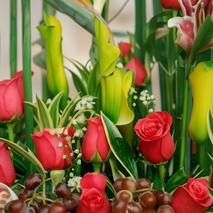 Primer plano extremo de Arreglo Floral con Frutas Akebia, mostrando rosas rojas vibrantes, uvas frescas y follaje verde con g