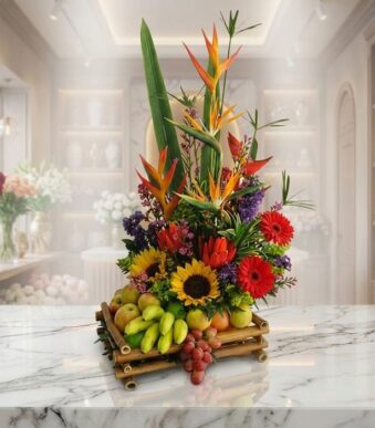 Arreglo floral exótico 'Bahamas' con aves del paraíso, girasoles, gerberas rojas y una base de frutas frescas como manzanas,