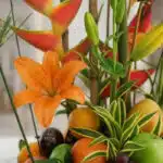 Primer plano extremo de un lirio naranja vibrante con gotas de rocío, parte del Arreglo Floral con Frutas Eclipse, mostrando