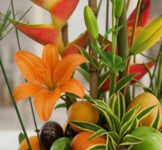 Primer plano extremo de un lirio naranja vibrante con gotas de rocío, parte del Arreglo Floral con Frutas Eclipse, mostrando