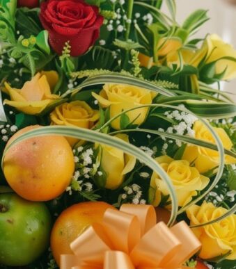Primer plano extremo de un arreglo floral con rosas amarillas y rojas, manzanas verdes y naranjas, con sutiles gotas de rocío