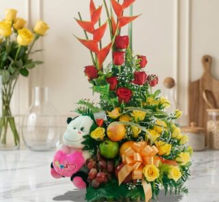 Arreglo Floral con Frutas Encanto, con rosas rojas y amarillas, aves del paraíso, uvas, manzanas, naranjas y un peluche, sobr