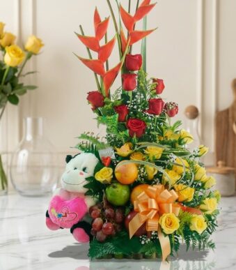 Arreglo Floral con Frutas Encanto, con rosas rojas y amarillas, aves del paraíso, uvas, manzanas, naranjas y un peluche, sobr