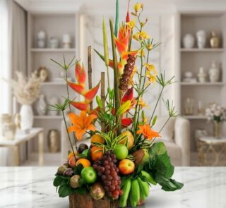 Arreglo floral con frutas exóticas, lirios naranjas, orquídeas amarillas y heliconias rojas, sobre base de madera rústica en