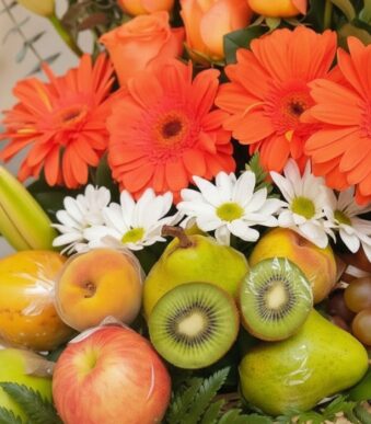 Primer plano extremo de Arreglo Floral con Frutas Hadar, mostrando gerberas naranjas, margaritas blancas, peras, kiwis, manza